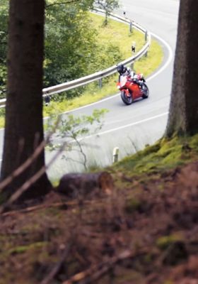 Kurvenfahrt eines Motorrades mit Bäumen im Vordergrund